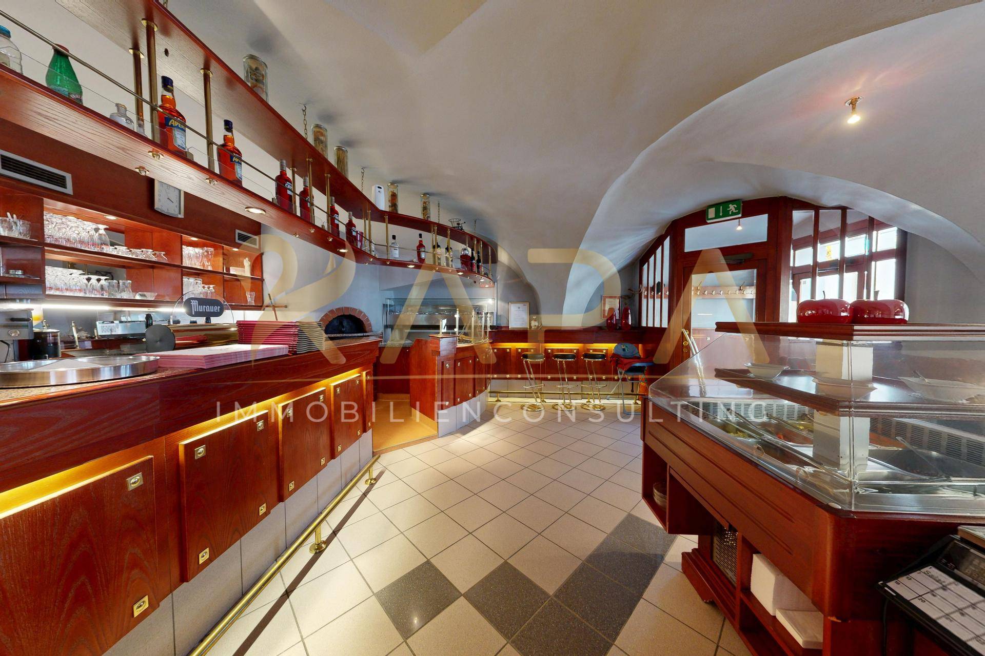 Innenansicht einer Bar oder eines Cafés mit gewölbter Decke und Holztheke.