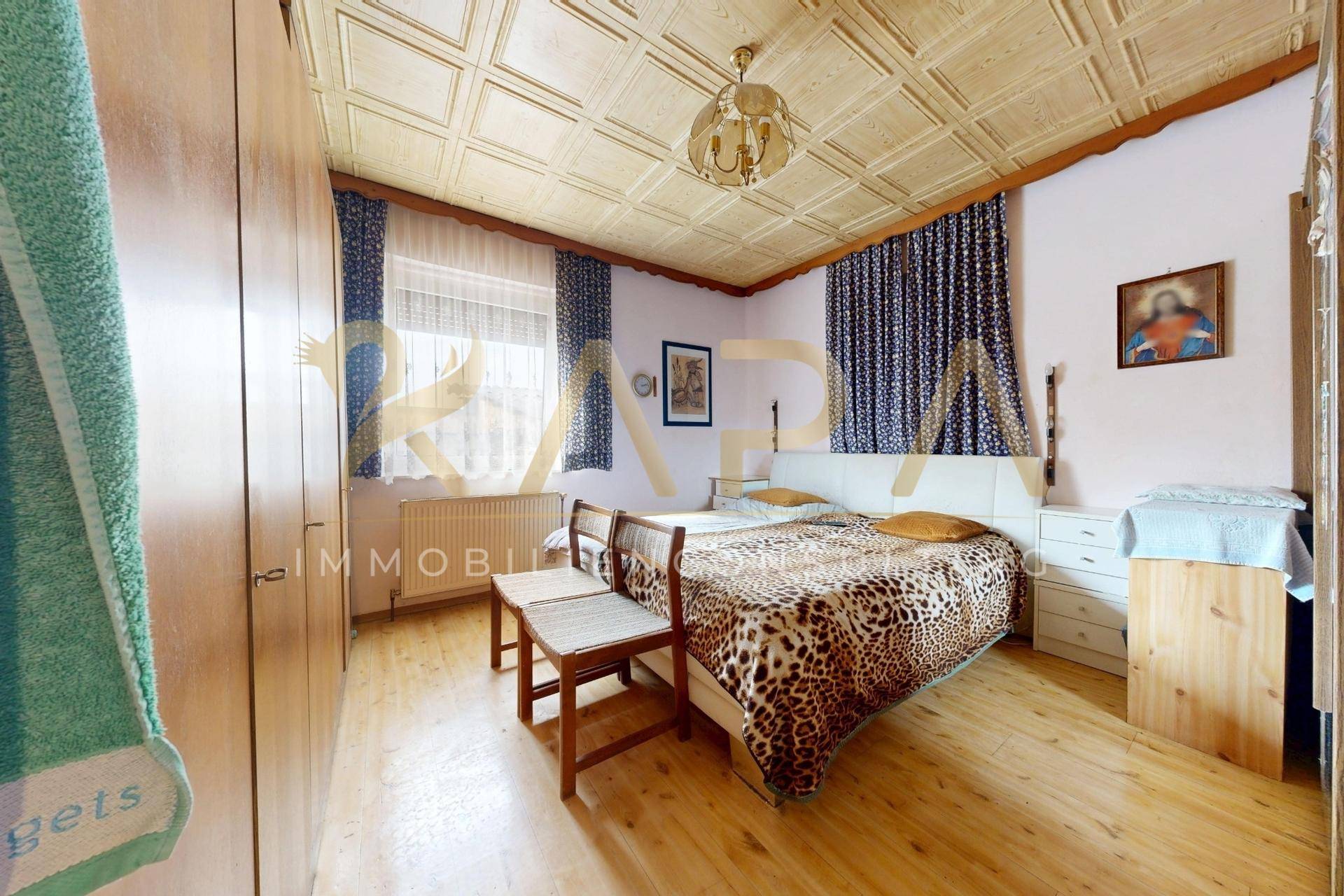 Schlafzimmer mit Holzboden, gemusterter Decke, Doppelbett und Holzschränken.