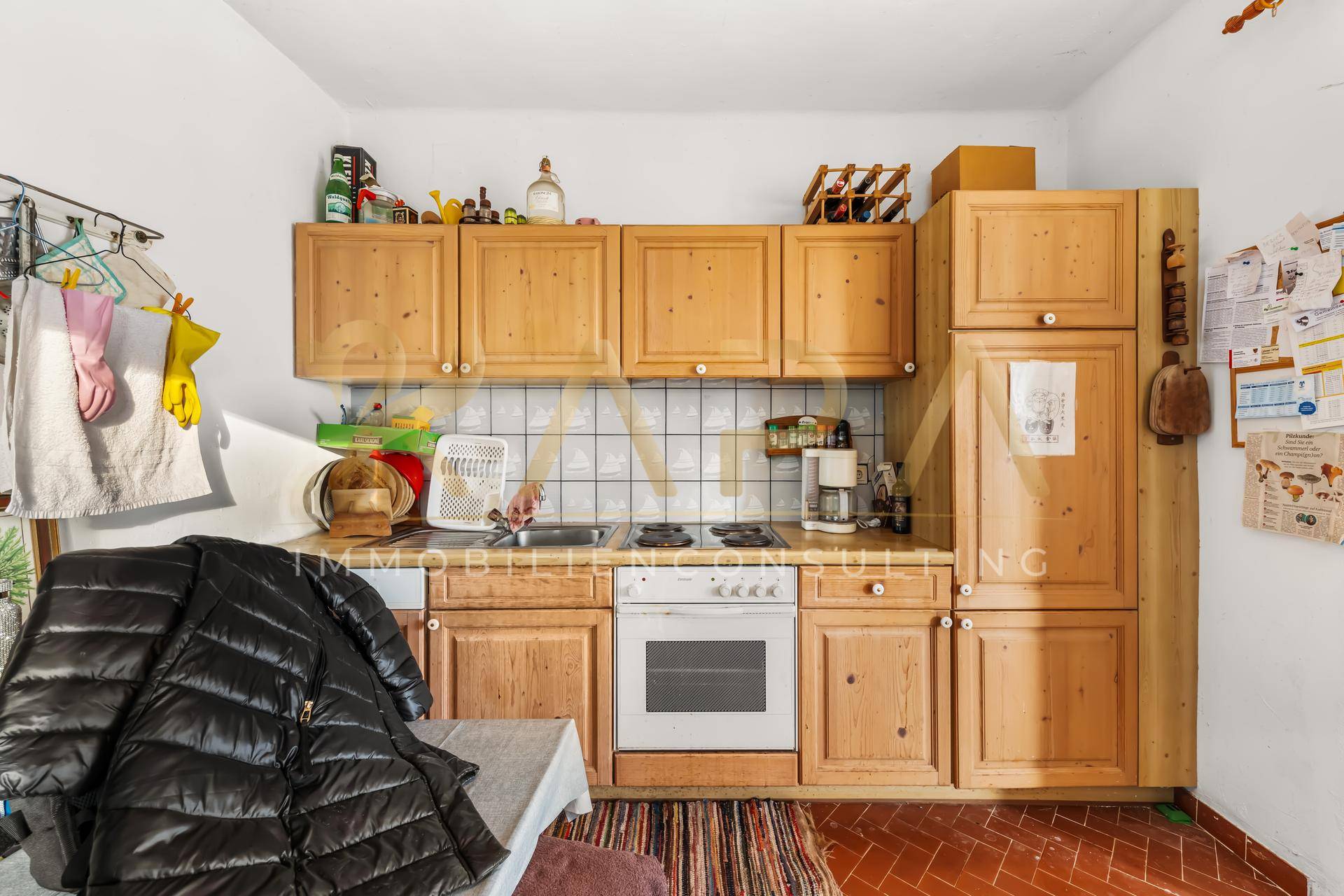 Funktionale Küche mit Holzschränken, weiß gefliestem Spritzschutz und einfacher Ausstattung.