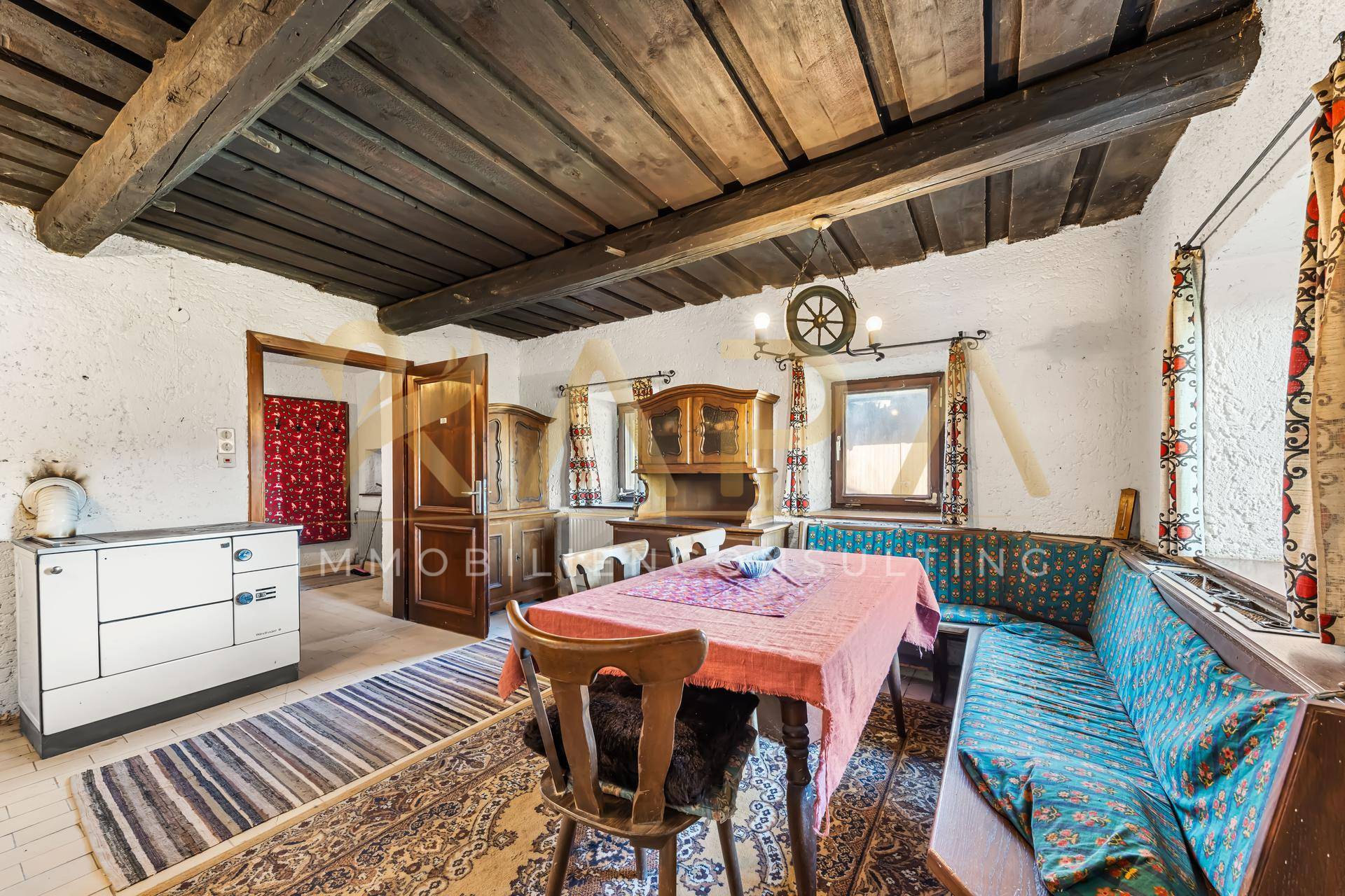 Rustikaler Essbereich mit Holzbalkendecke, traditionellen Möbeln und einem Kachelofen.