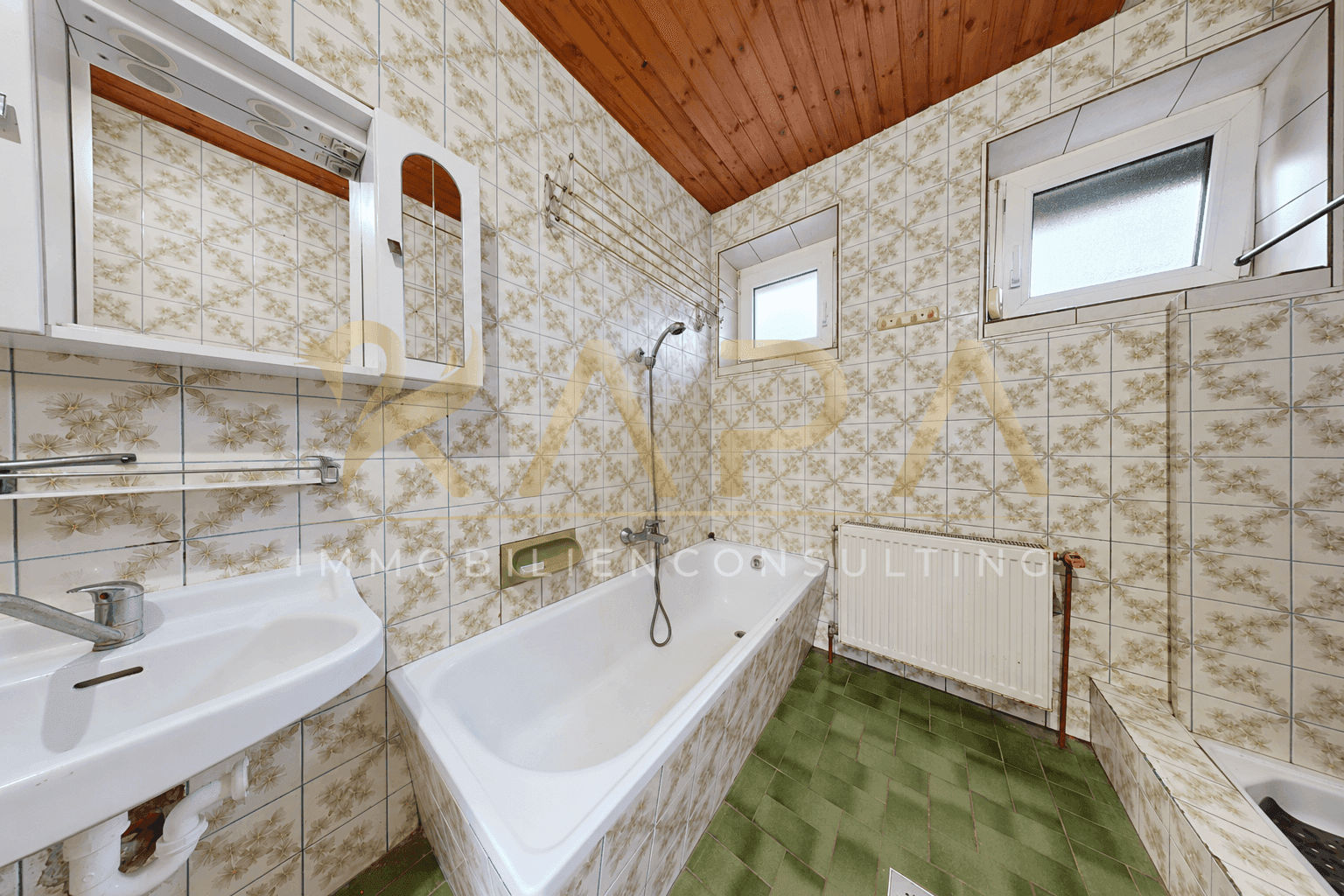 Badezimmer im 80er-Jahre-Stil mit gemusterten Fliesen, Badewanne und Holzdecke.