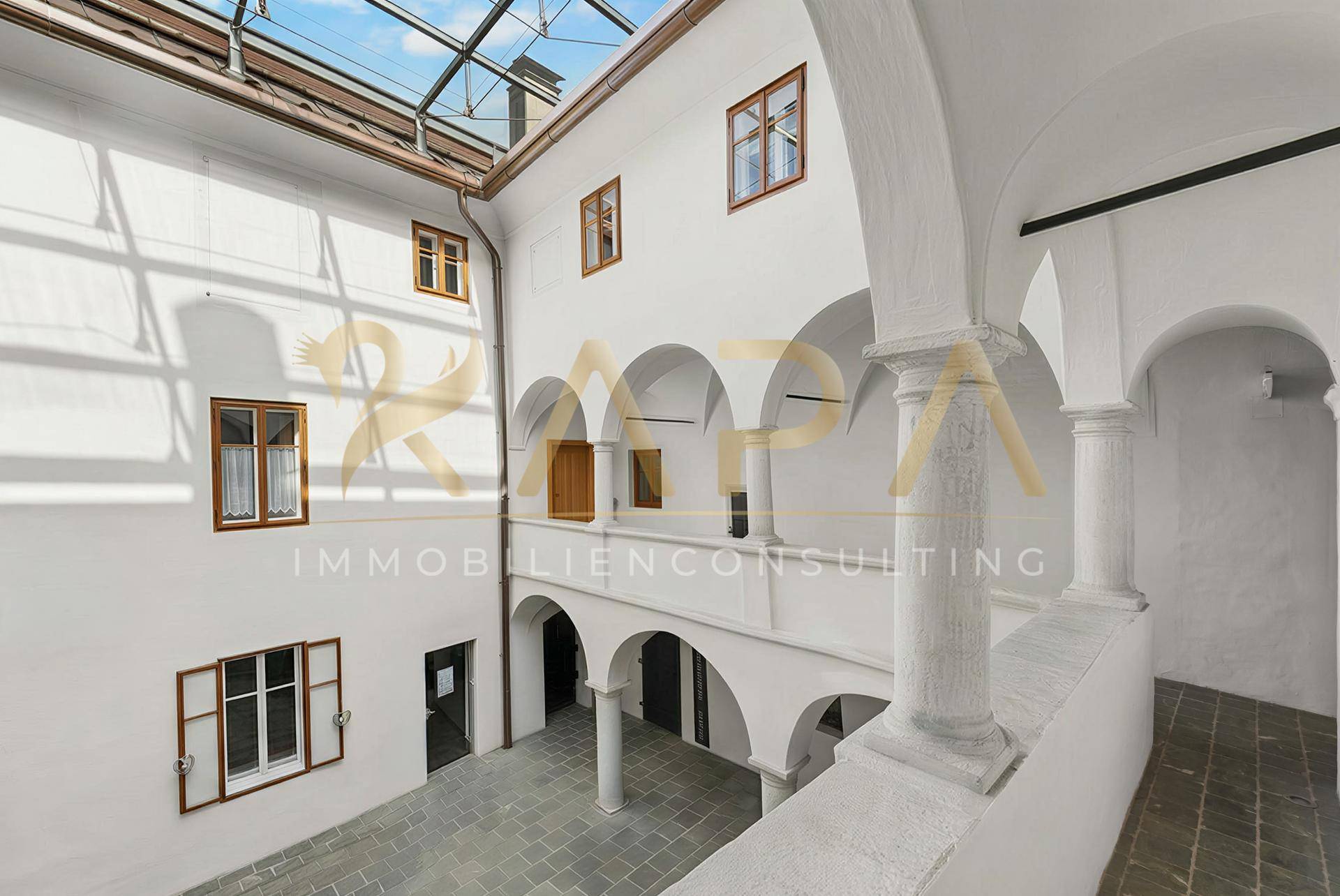Historischer Innenhof mit Arkaden und einem Glasdach, das viel Licht spendet.