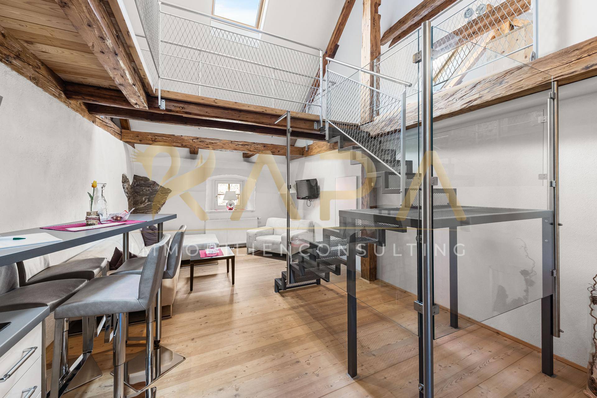 Offener Wohnbereich im Loft-Stil mit Holzbalken, Galerie und moderner Treppe.