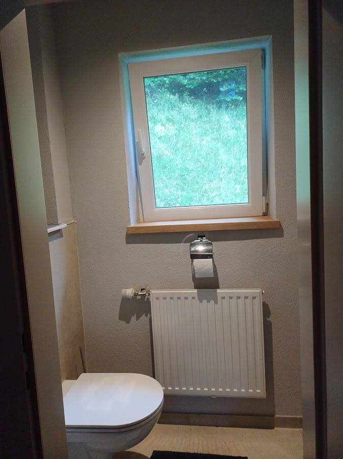 Kleines WC mit Fenster und Heizkörper, praktisch und funktional gestaltet.