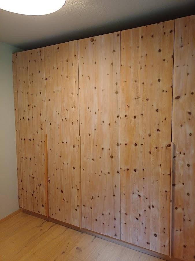 Großer, raumhoher Einbauschrank aus hellem Holz mit natürlicher Maserung und Astlöchern.
