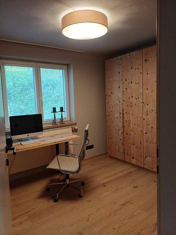 Funktionales Arbeitszimmer mit großem Fenster, Holzschrank und Schreibtisch für produktives Arbeiten.