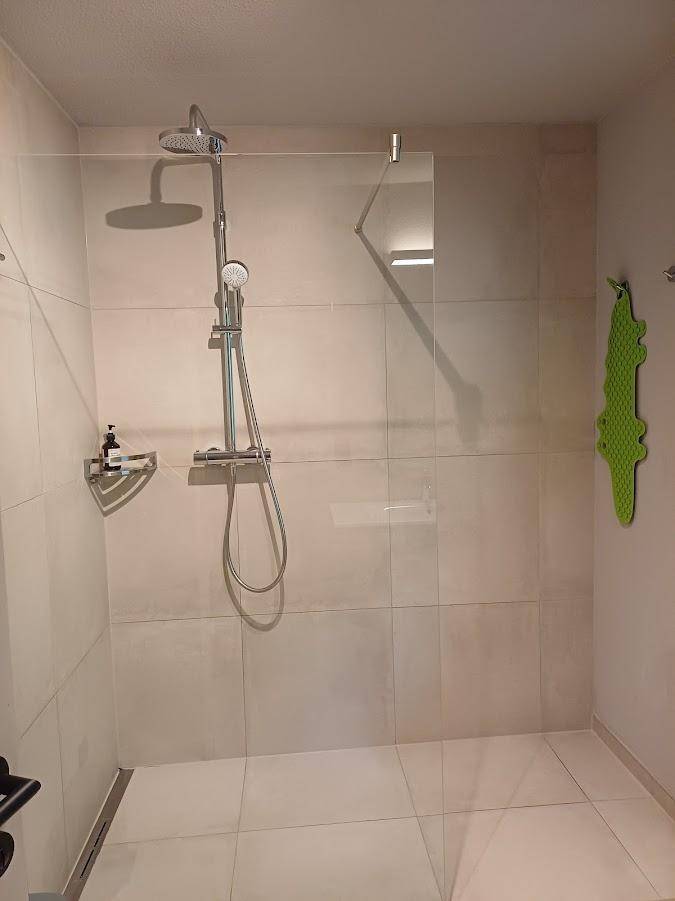Modernes Badezimmer mit ebenerdiger Dusche und großformatigen Fliesen.