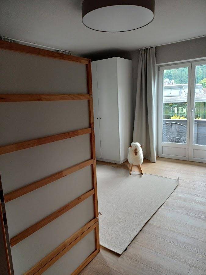 Helles Schlafzimmer mit weißem Kleiderschrank und Zugang zu einem Außenbereich.
