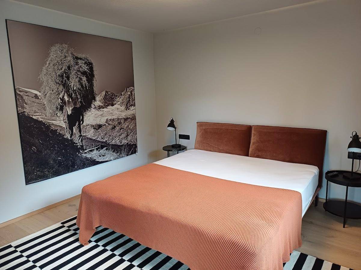 Schlafzimmer mit Doppelbett, Holzboden und großformatigem Kunstwerk an der Wand.