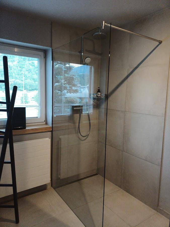 Modernes Badezimmer mit ebenerdiger Dusche, Fenster und hellen Fliesen.