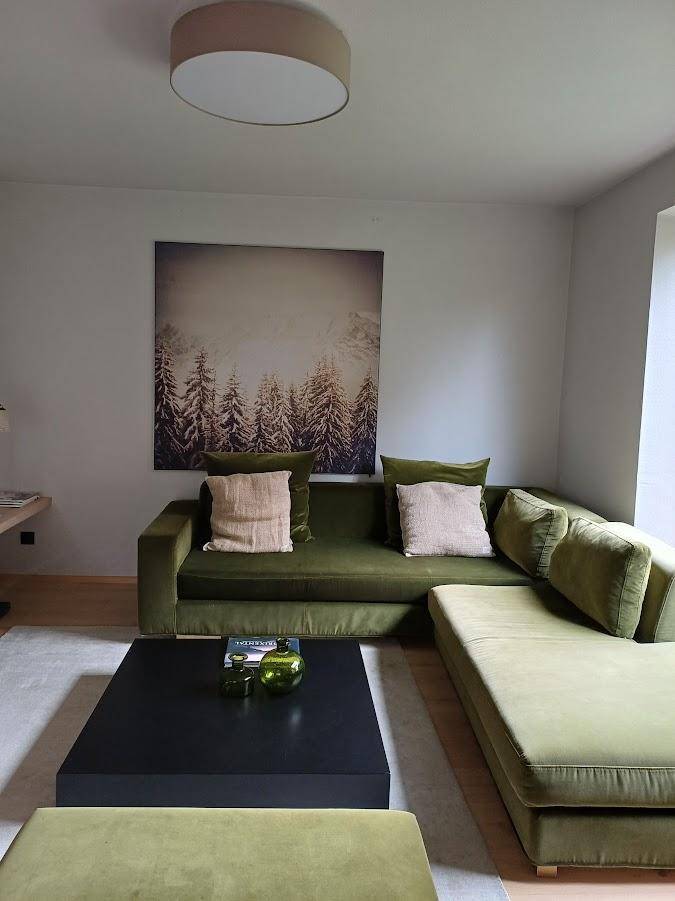 Gemütliches Wohnzimmer mit einer großen grünen Eckcouch und modernem Couchtisch.
