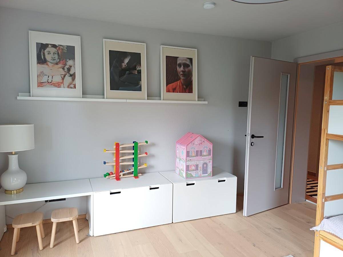 Kinderzimmer oder Gästezimmer mit Schreibtisch, Stauraum und dekorativen Bildern.