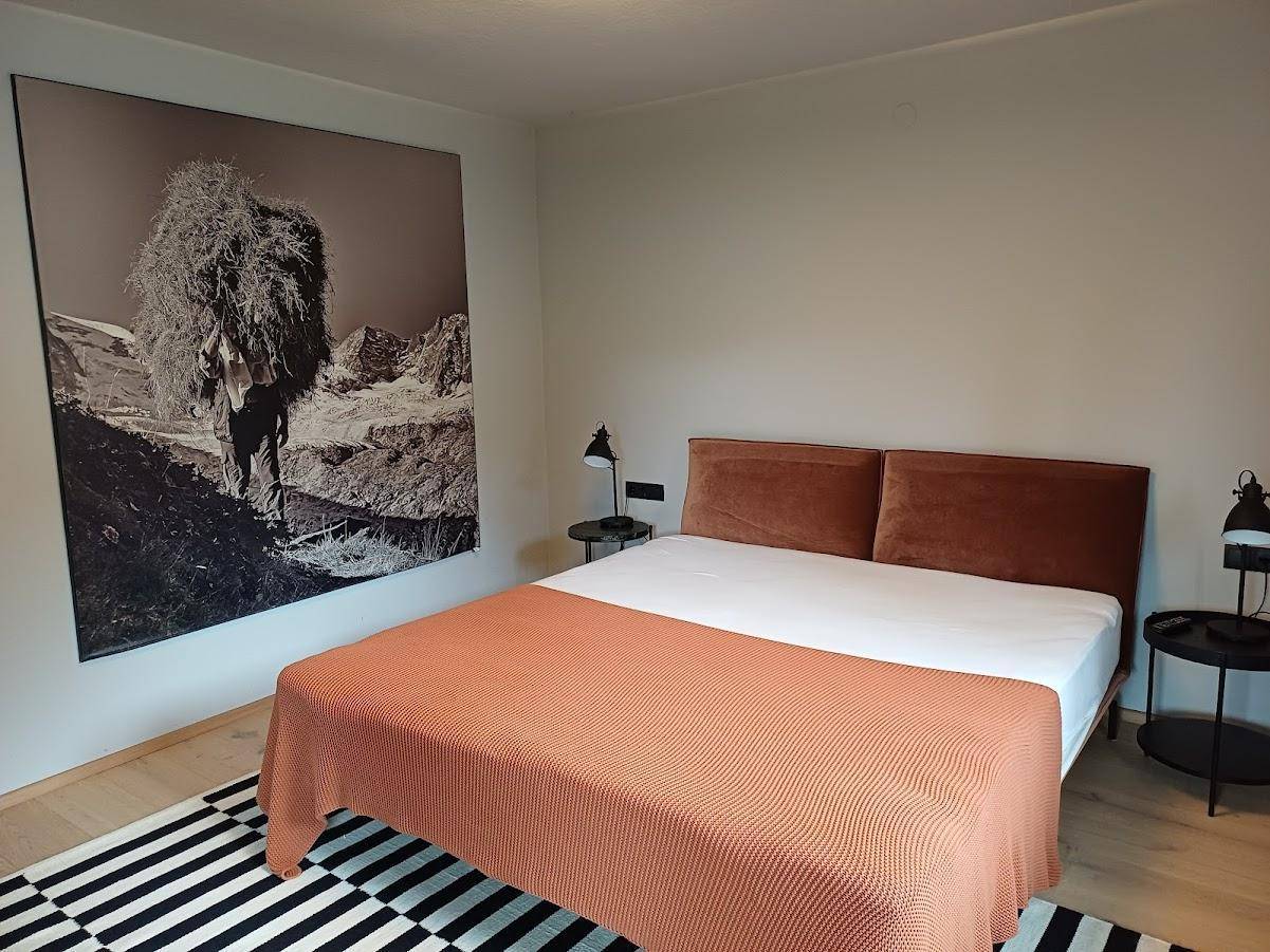 Gemütliches Schlafzimmer mit Doppelbett, Nachttischen und großem Wandbild in Schwarz-Weiß.