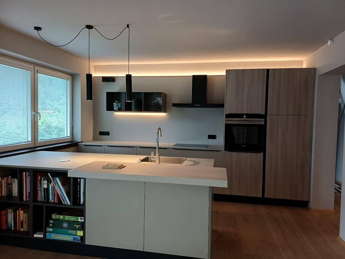 Moderne Einbauküche mit Kochinsel, integrierten Geräten und viel Stauraum.