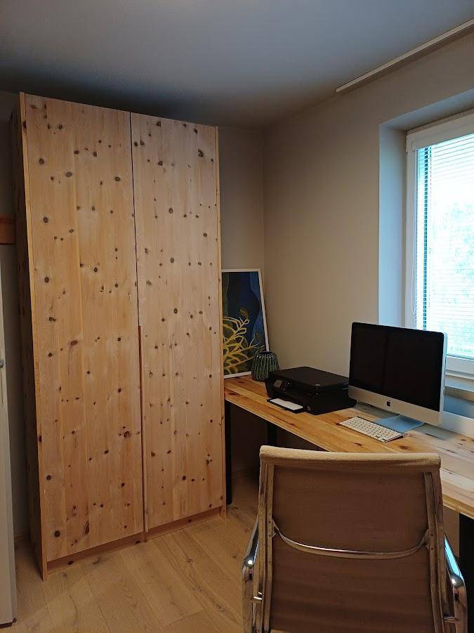 Helles Arbeitszimmer mit Holzschrank, Schreibtisch und Fenster für natürliche Belichtung.