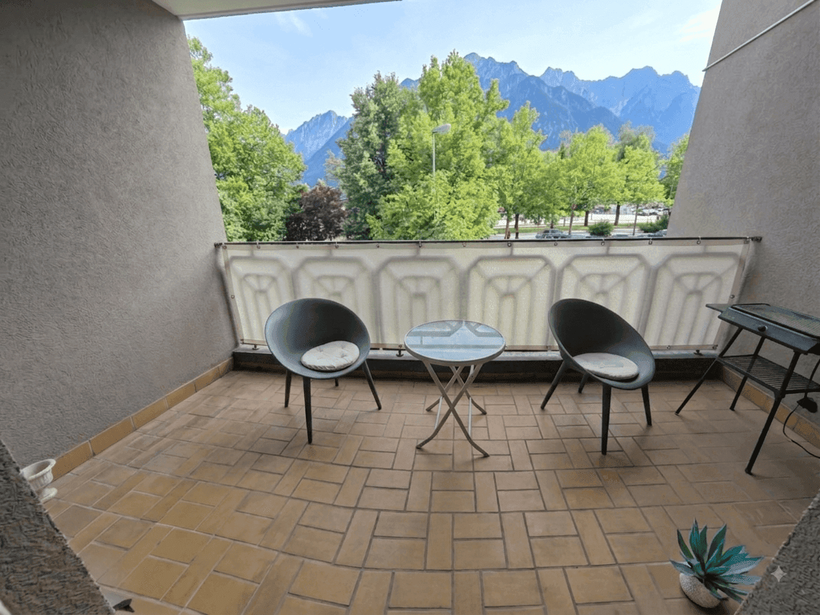 Gemütlicher Balkon mit Fliesenboden, Sitzgelegenheiten und beeindruckendem Bergblick in die Ferne.