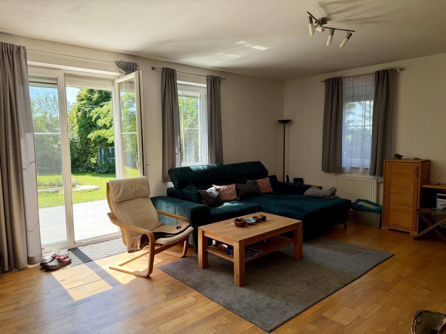 Helles Wohnzimmer mit Zugang zur Terrasse und zum Garten, ausgestattet mit einem bequemen Sofa.