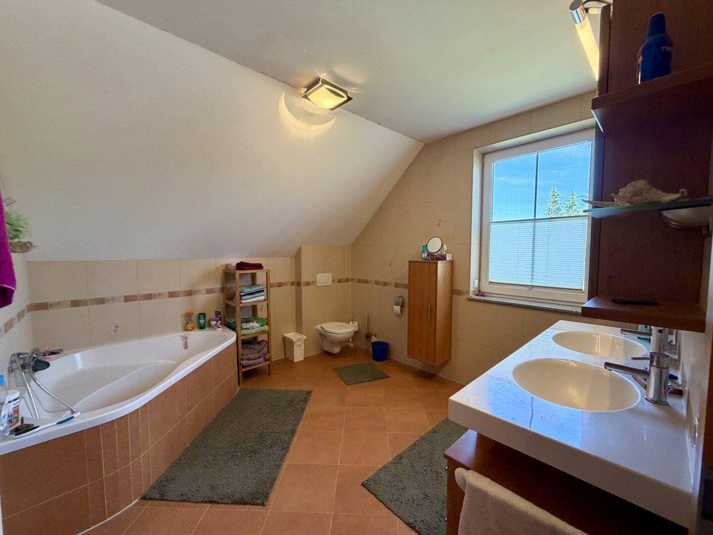 Geräumiges Badezimmer mit Eckbadewanne, Doppelwaschbecken und gefliesten Oberflächen.