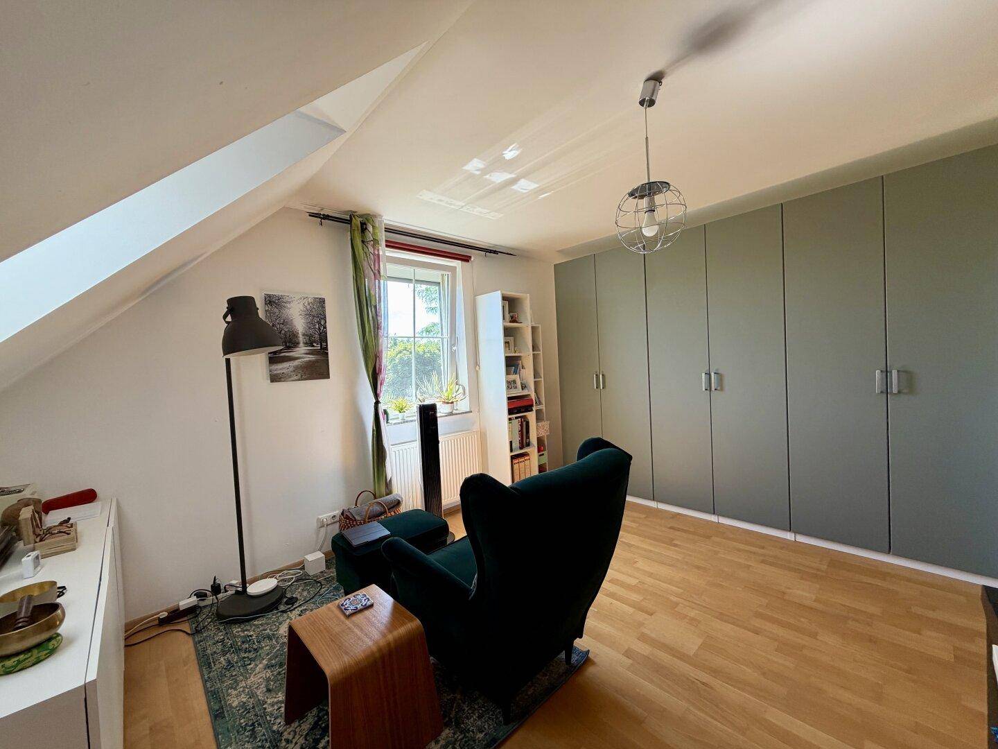 Dachgeschosszimmer mit integrierten Kleiderschränken, Leseecke und Holzboden.