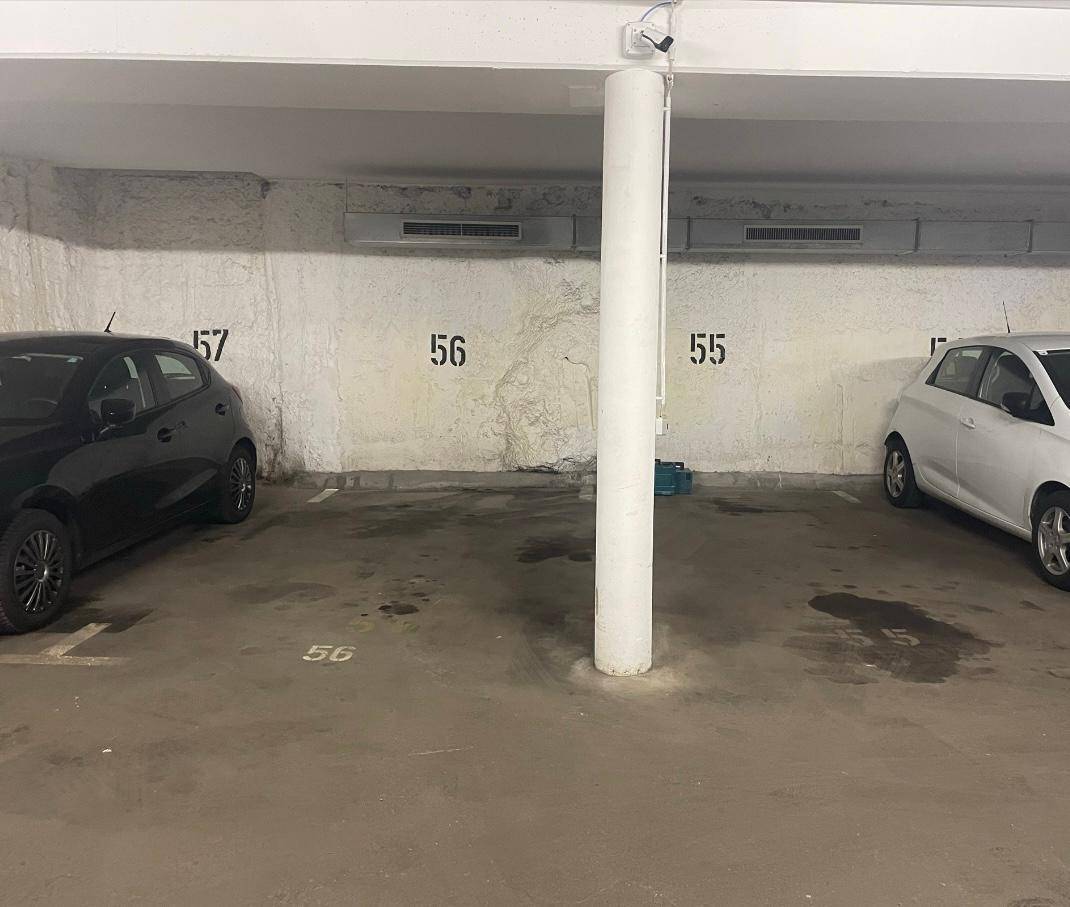 Zwei Stellplätze in einer Tiefgarage mit Betonwänden, einem Pfeiler und Überwachungskamera.