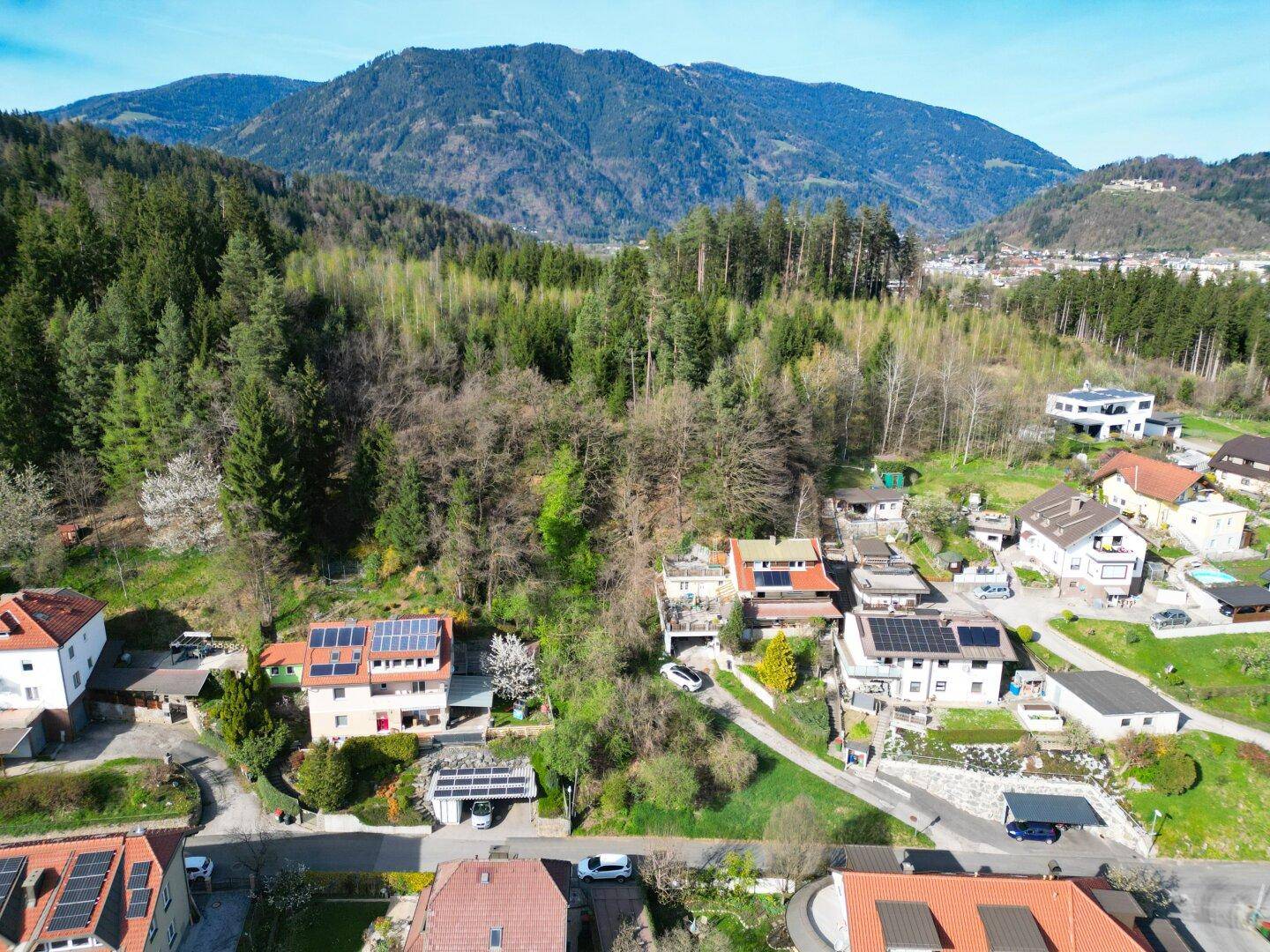 Wohngebiet am Waldrand mit Häusern, die Solaranlagen auf den Dächern und Bergblick bieten.
