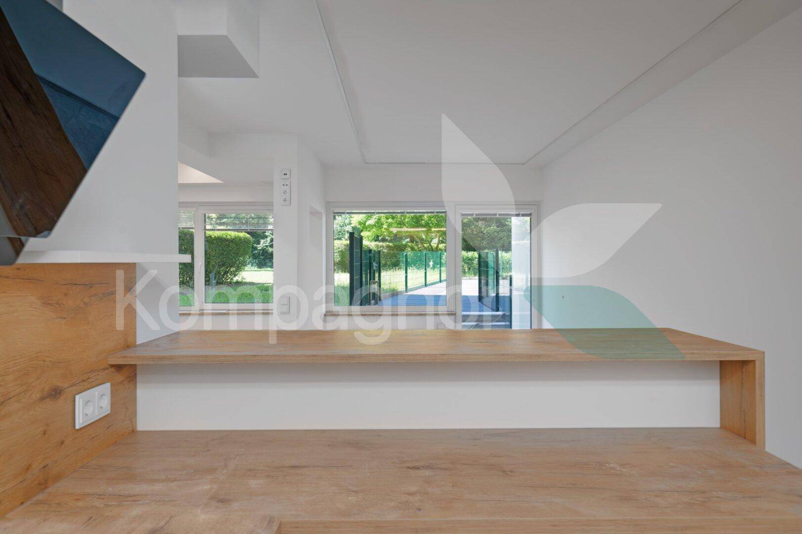 Moderne Holztheke in einem offenen Bereich mit Blick auf den grünen Außenbereich.
