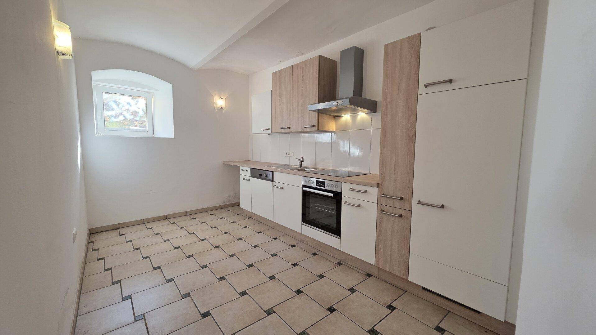 Moderne Einbauküche mit hellen Fronten, Fliesenboden und einem charmanten Bogenfenster.