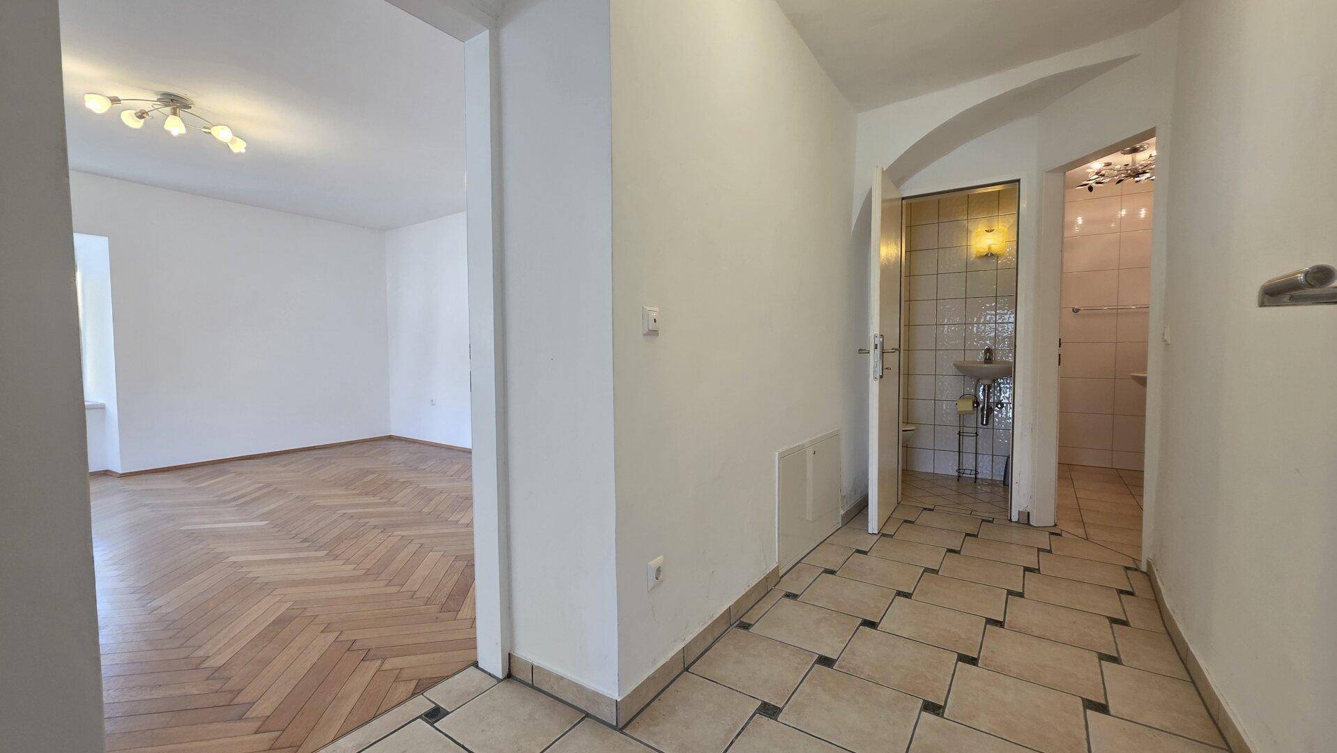 Heller Flur mit Fliesenboden, der zum Wohnbereich und einem Badezimmer führt.