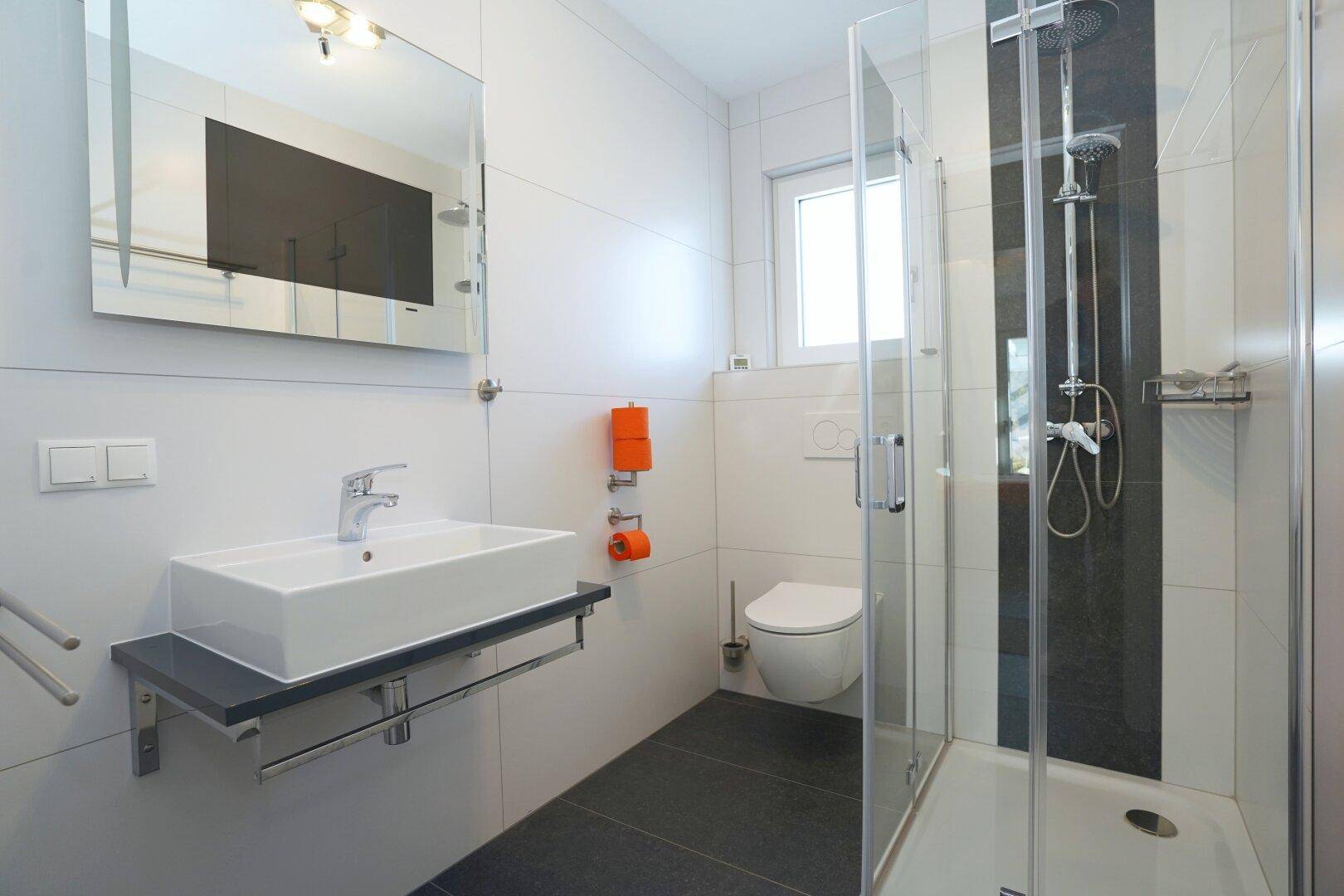 Helles Badezimmer mit Dusche, WC und Fenster für natürliche Belüftung.