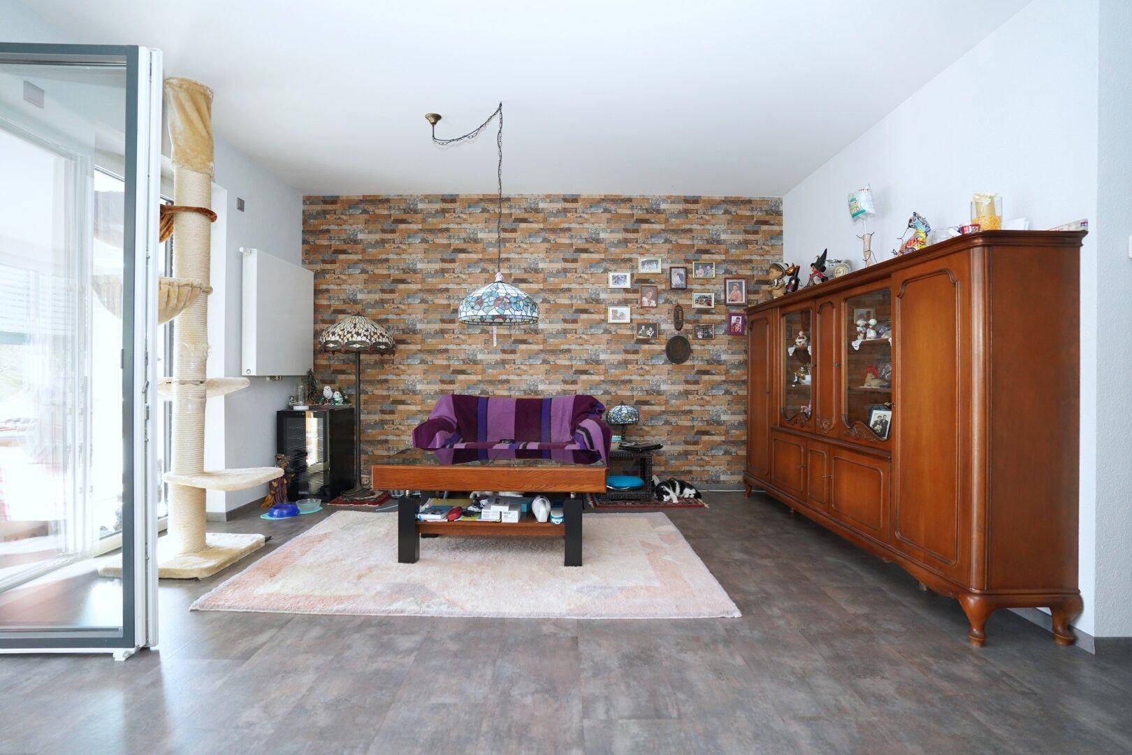 Gemütliches Wohnzimmer mit Akzentwand in Steinoptik und klassischem Holzschrank.