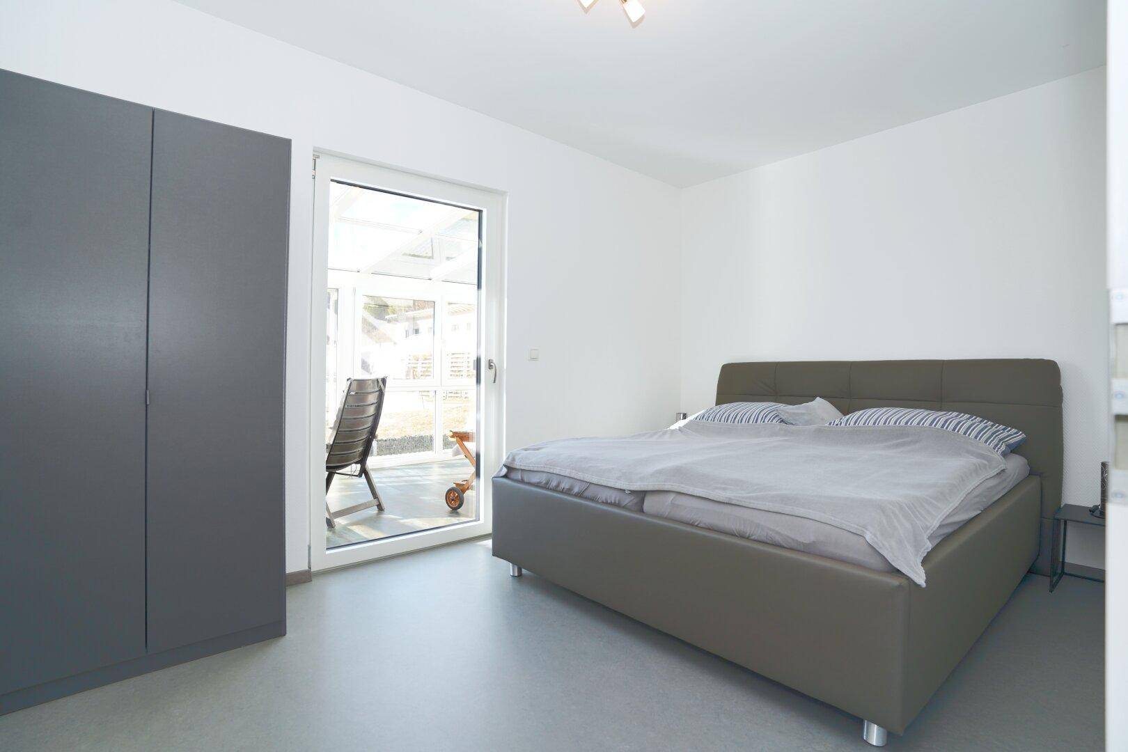 Schlafzimmer mit Doppelbett, modernem Kleiderschrank und Zugang zur Terrasse.