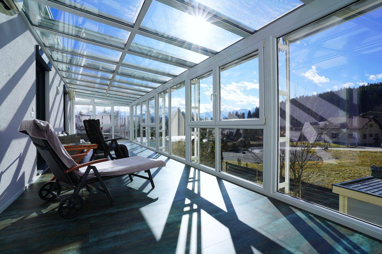 Heller Wintergarten mit Glasdach und Liegestühlen, ideal zum Entspannen mit Weitblick.