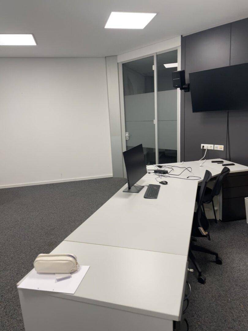 Gut ausgestattetes Büro mit mehreren Arbeitsplätzen, modernen Möbeln und Teppichboden.
