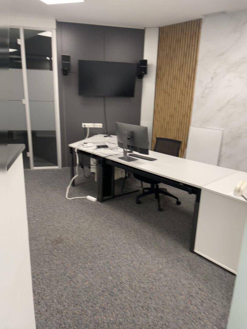 Modernes Büro mit Schreibtischen, einem Wandfernseher und einer dekorativen Holzwand.