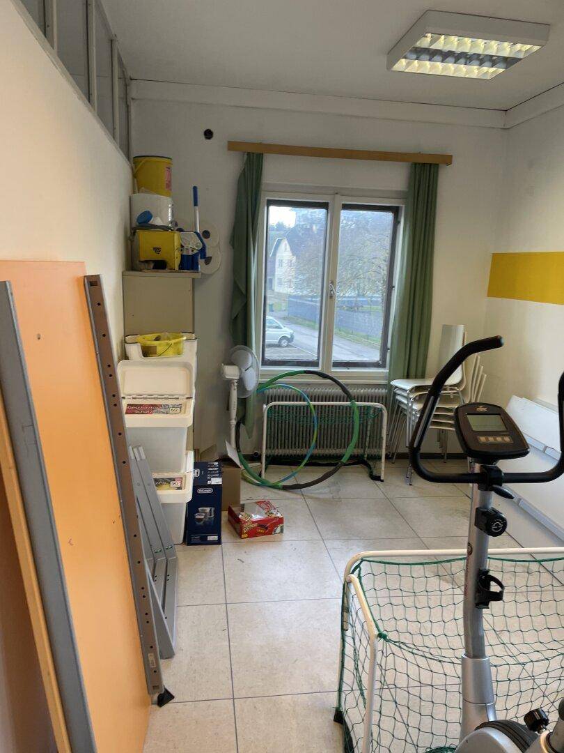 Abstellraum mit Fitnessgeräten, Kartons und einem Fenster mit Blick nach draußen.