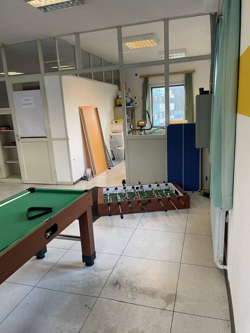 Freizeitraum mit Billardtisch, Kicker und Glasabtrennungen, die den Raum strukturieren.