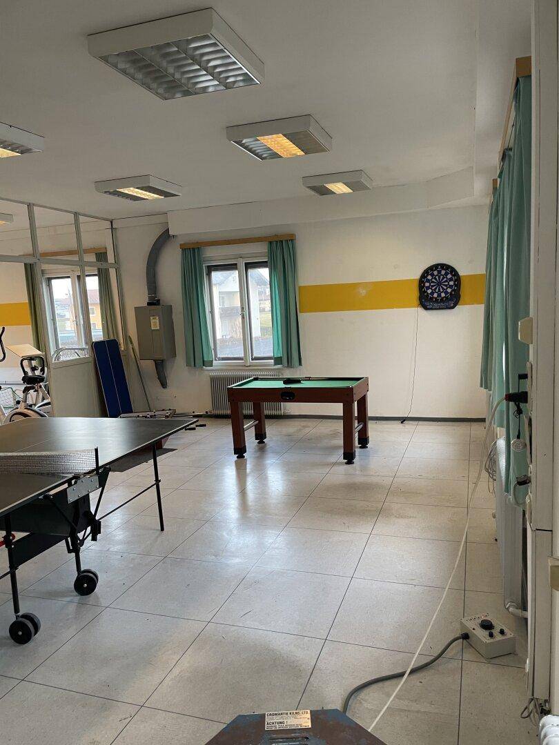 Geräumiger Freizeitraum mit Tischtennisplatte, Billardtisch und Dartscheibe, gut beleuchtet.