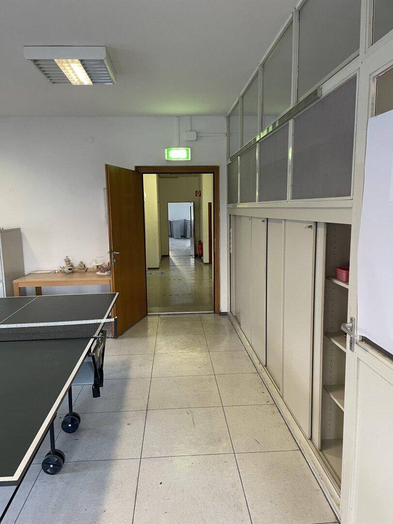 Freizeitraum mit Tischtennisplatte und Blick auf einen Flur, der zu weiteren Bereichen führt.