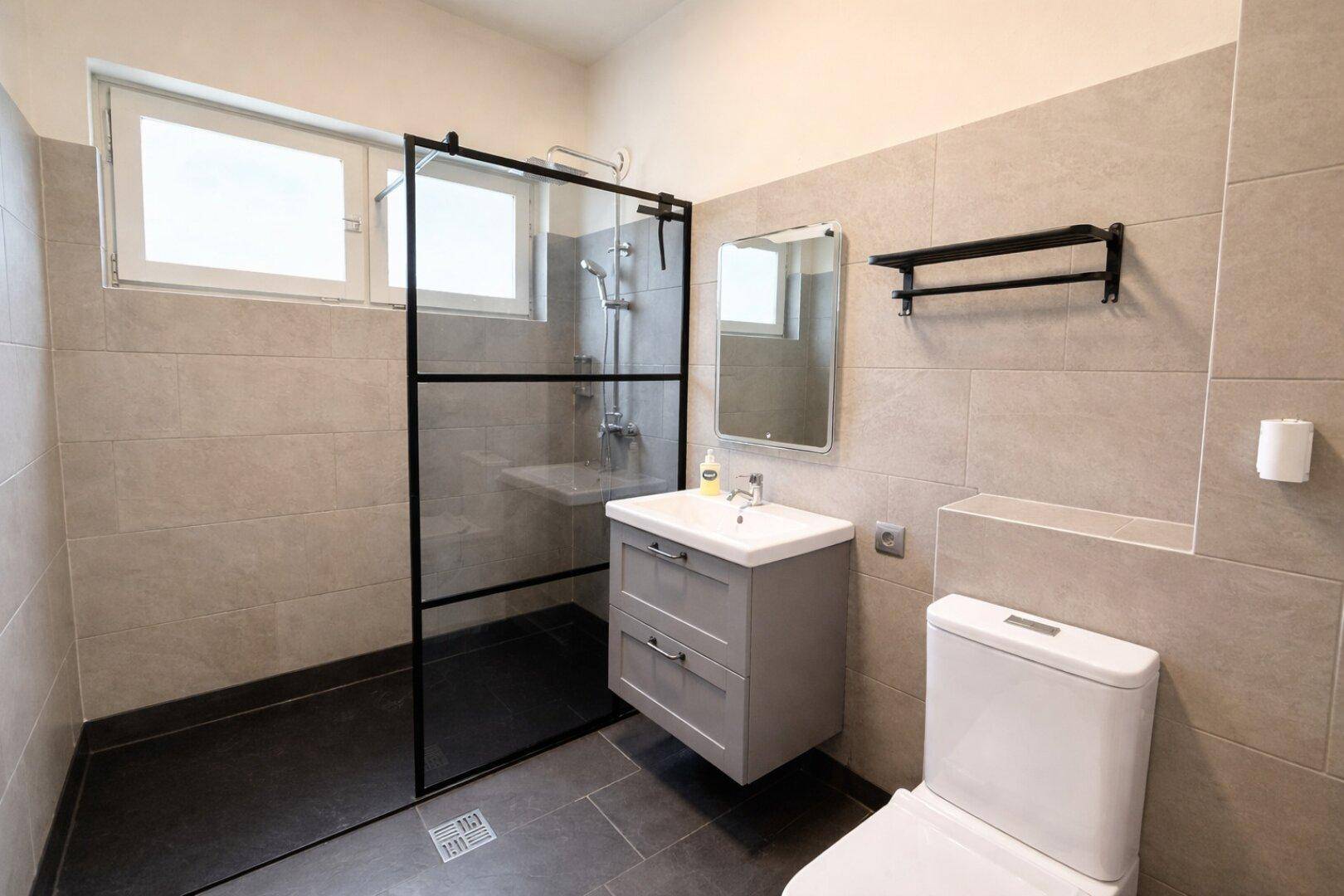Modernes Badezimmer mit begehbarer Dusche, Waschbecken und Fenster.