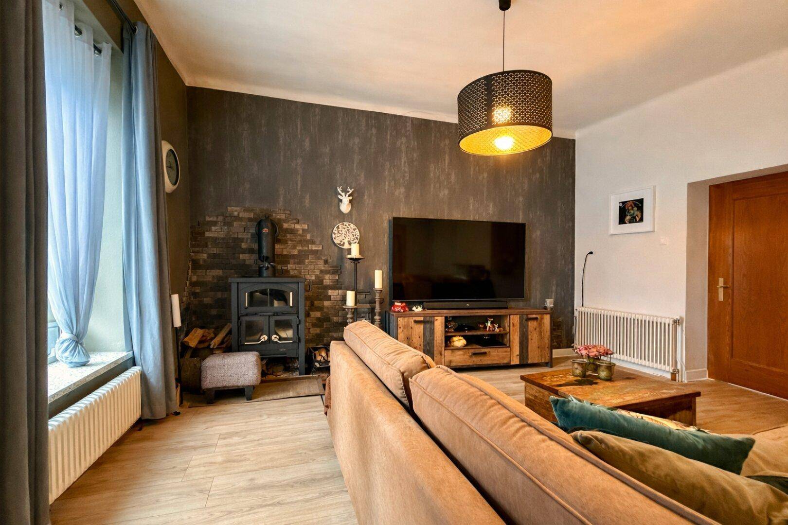 Gemütliches Wohnzimmer mit Sofa, Kaminofen und Fernseher.