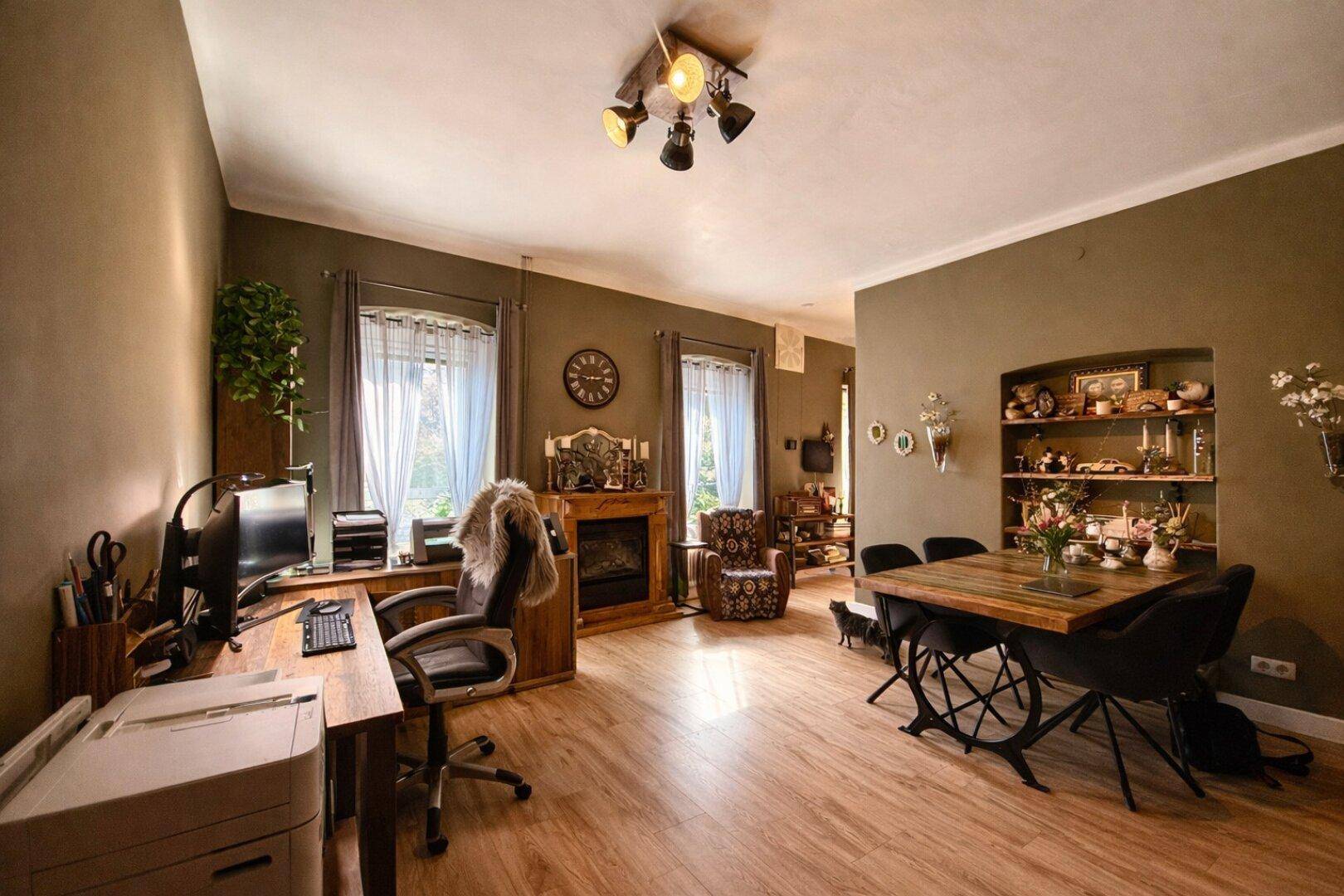 Geräumiger Wohn-Essbereich mit Arbeitsplatz, Kamin und Holzboden.