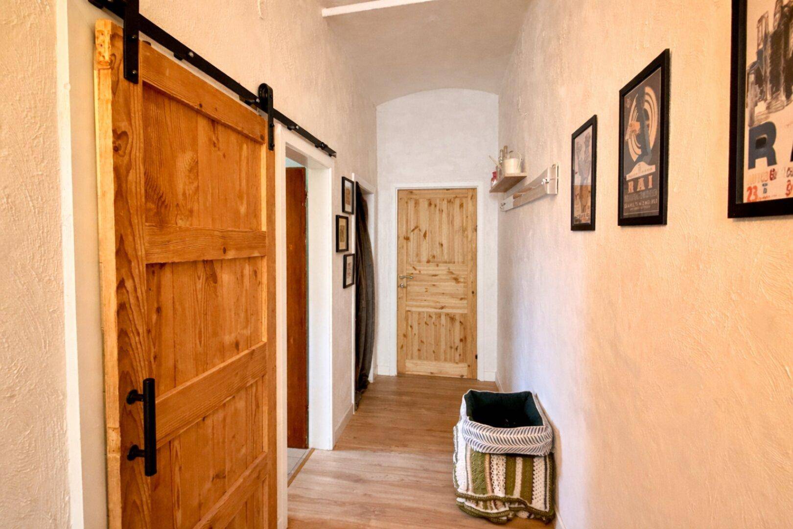 Heller Flur mit Holzboden und rustikalen Schiebetüren.