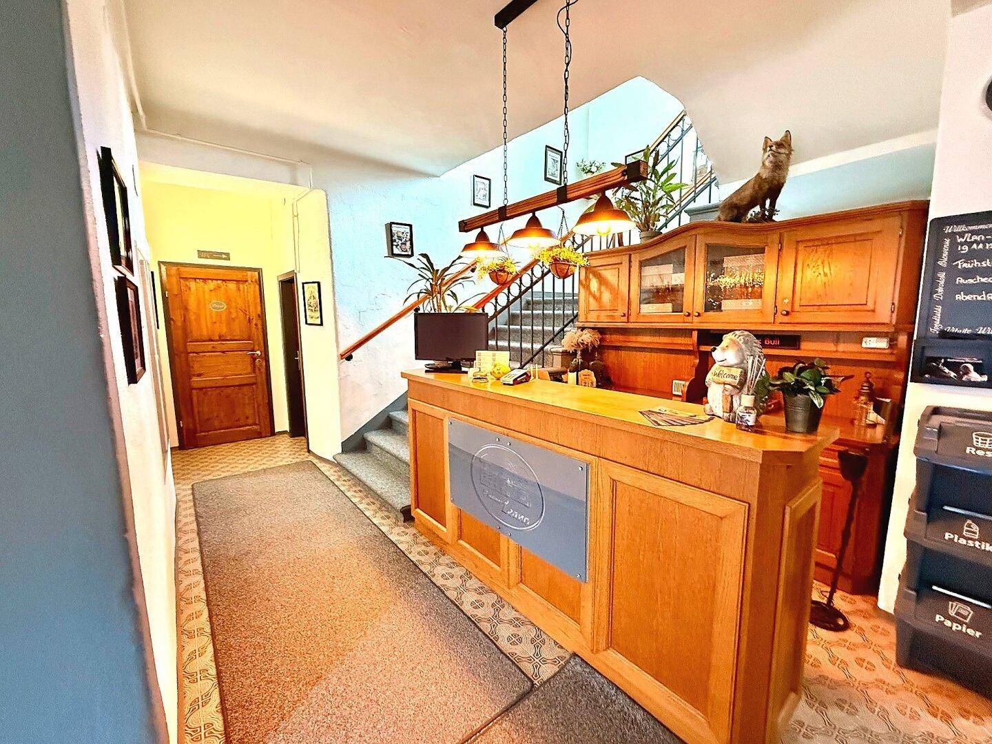 Empfangsbereich mit Holztheke, Treppe und traditioneller Dekoration.