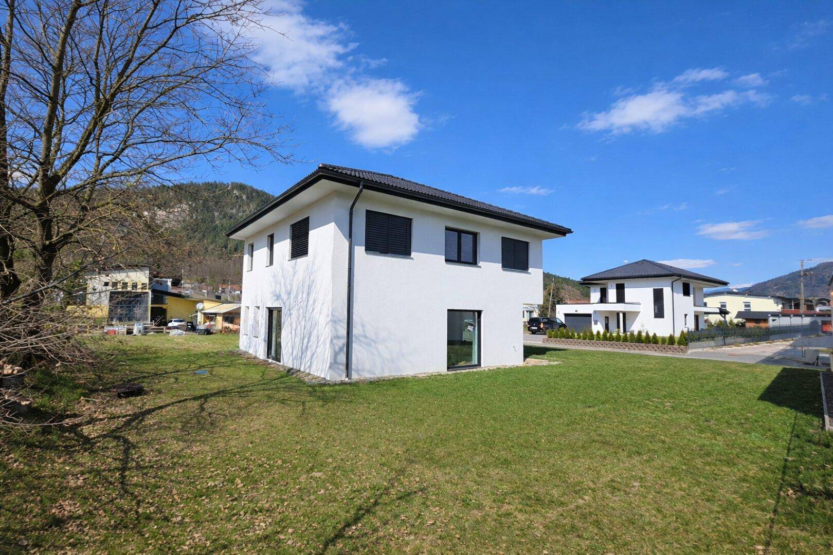 Freistehendes Einfamilienhaus mit gepflegtem Rasen und Blick auf die umliegende Landschaft.