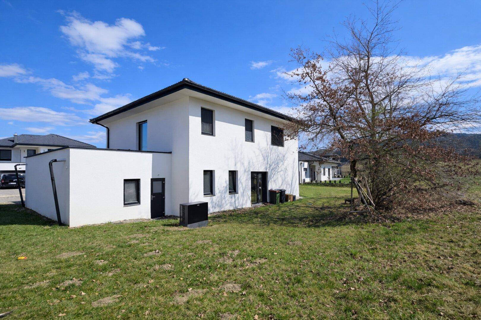 Rückansicht des modernen Einfamilienhauses mit Garten und Blick auf die Natur.
