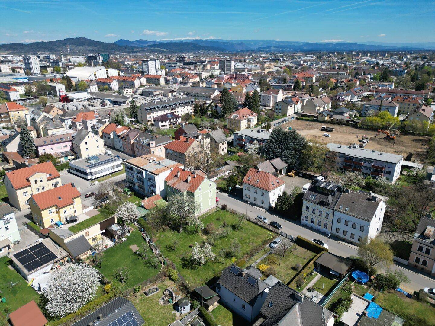 Weitläufige Luftaufnahme der Stadt mit Wohngebieten und Bergen im Hintergrund.
