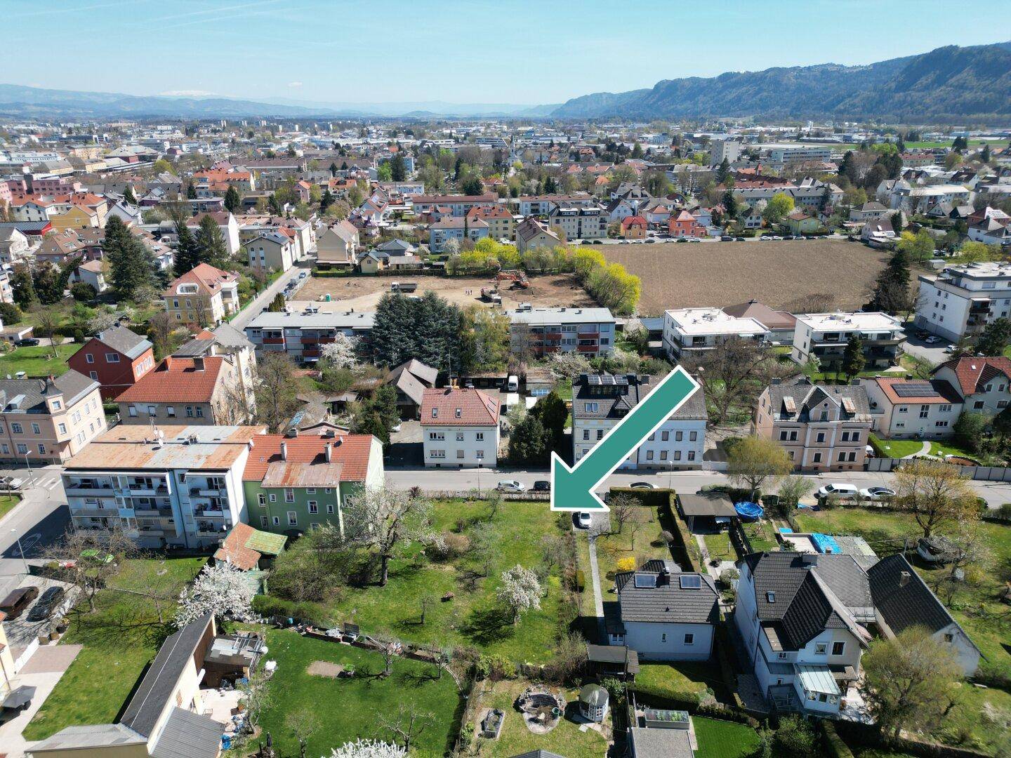 Übersichtliche Luftaufnahme der Stadt mit einem Pfeil, der auf das zum Verkauf stehende Grundstück zeigt.
