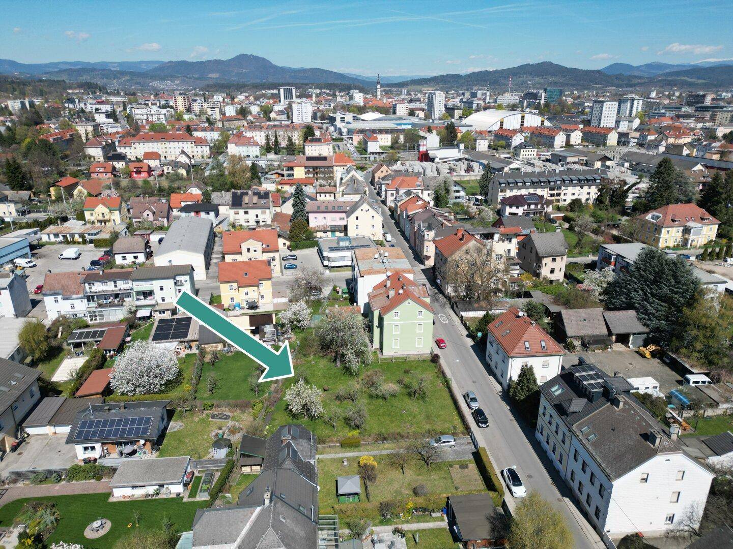 Übersichtliche Luftaufnahme der Stadt mit einem Pfeil, der auf das zum Verkauf stehende Grundstück zeigt.