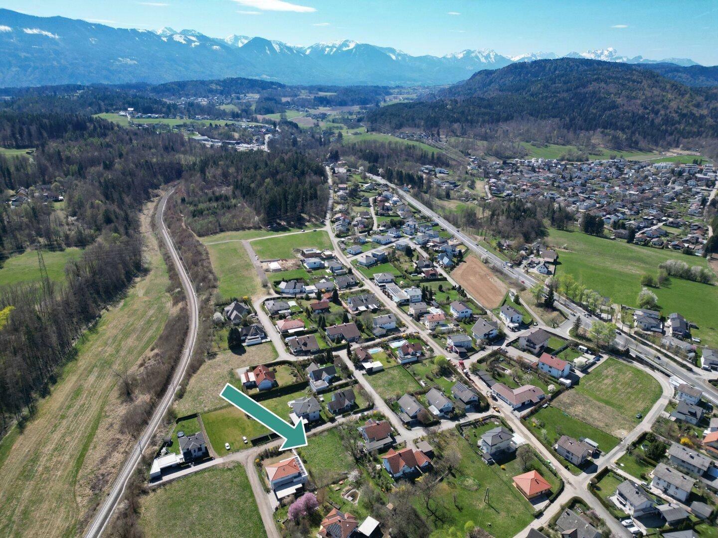 Luftaufnahme eines Wohngebiets mit einem markierten Haus und weitem Blick auf die Berglandschaft.