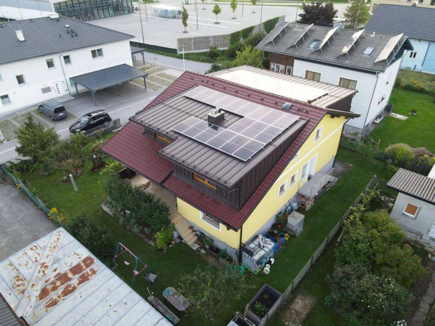 Luftaufnahme eines Einfamilienhauses mit Photovoltaikanlage auf dem Dach und großem Garten.